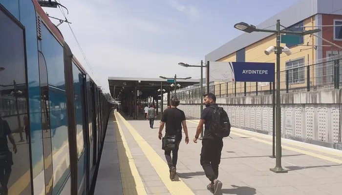 Aydıntepe Marmaray İstasyonu peronu: solda perona yanaşmış tren, sağda mavi AYDINTEPE tabelası ve sarı istasyon binası