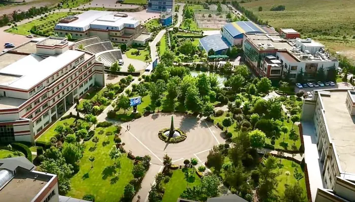 Okan Üniversitesi Tuzla yerleşkesinin havadan görünümü: fakülte binaları, açık amfi, ortada havuzlu meydan