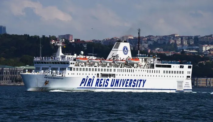Pîrî Reis Üniversitesi'nin eğitim gemisi İstanbul Boğazı'nda: gövdesinde üniversite adı, güvertede sıralanmış öğrenciler