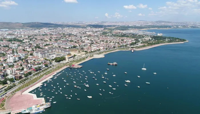 Tuzla kıyısının havadan görünümü: solda sahil yolu ve yerleşim, koyda demirlemiş tekneler, sağda Marmara Denizi